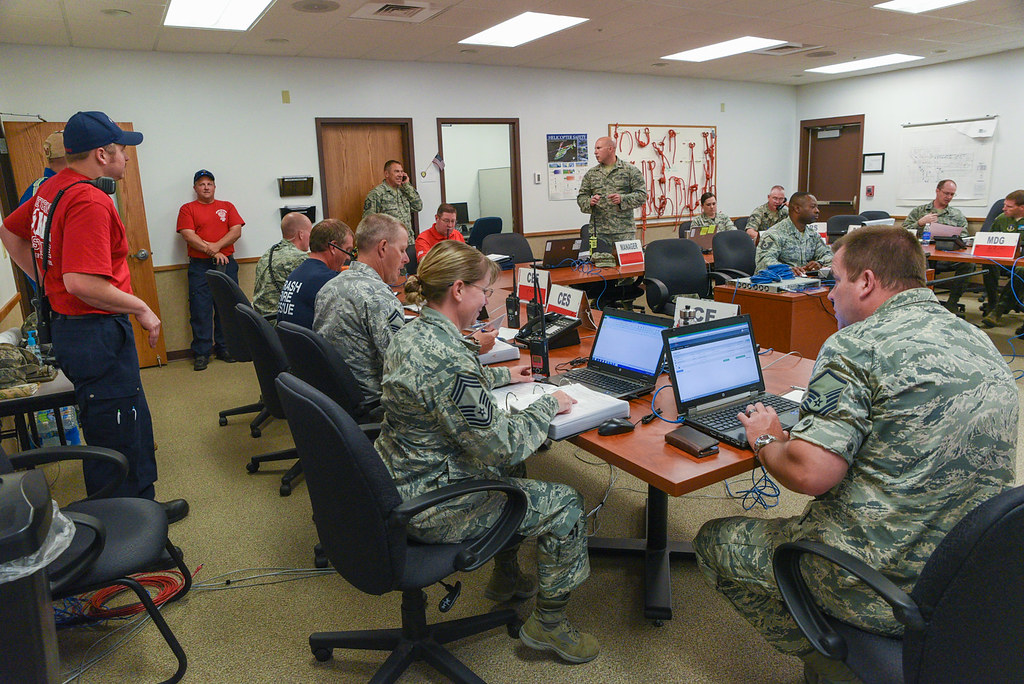 Emergency operations center staff use laptops and radios during a simulated incident.