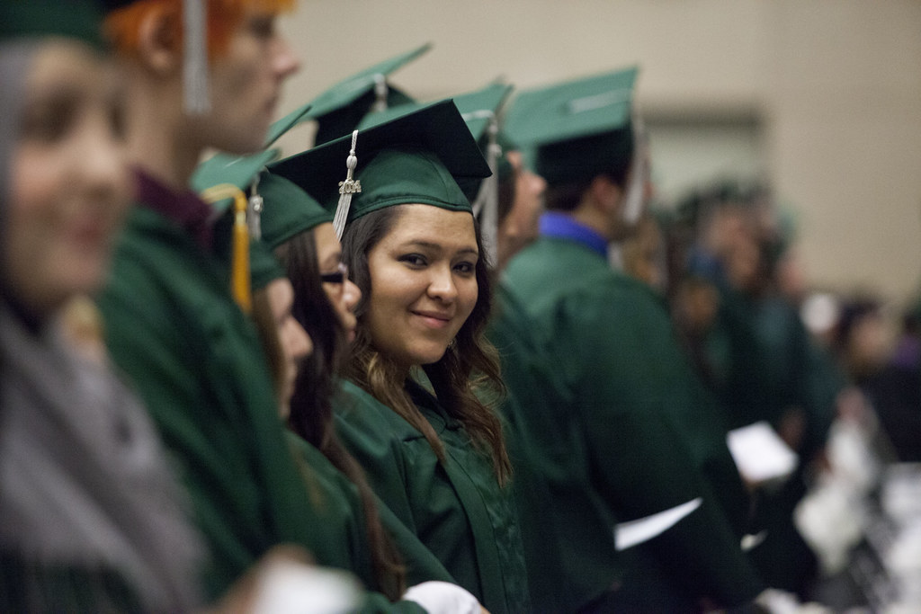 Graduates in green caps and gowns wait during a College of DuPage commencement ceremony.