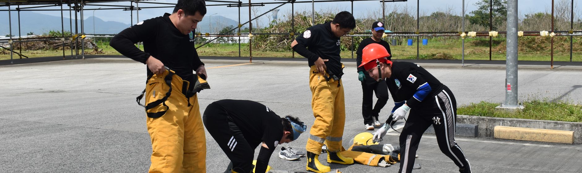 Emergency responders pulling on turnout gear during a timed drill on a training ground