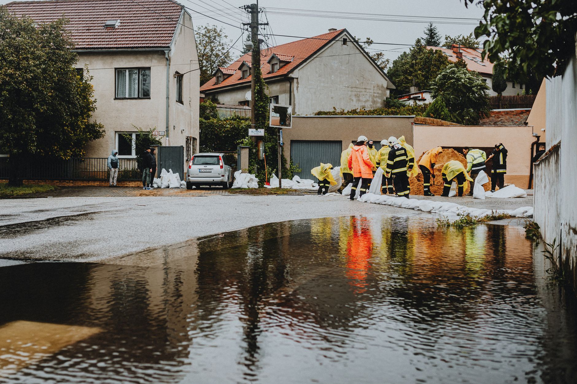 Emergency responders in high-visibility gear working in floodwater on a residential street